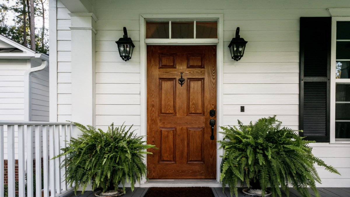 Dark wood front door on house with white siding