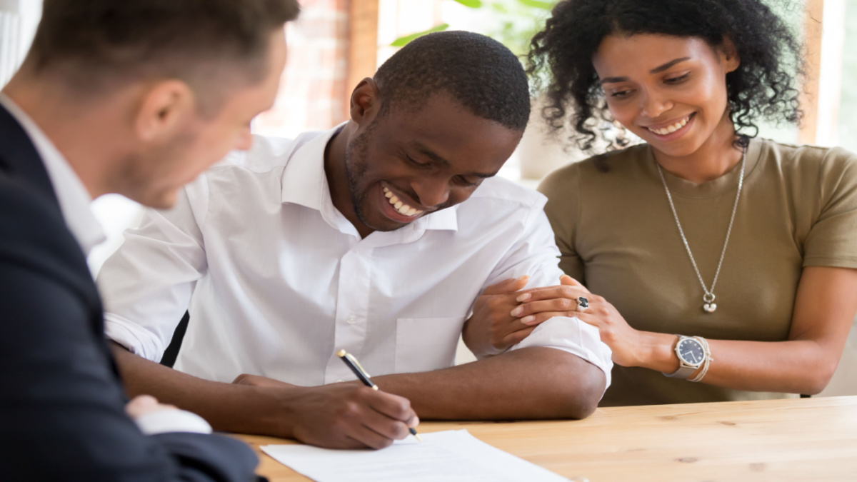 Couple signing house closing papers with real estate agent